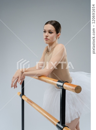 Ballet dancer practicing gracefully at the barre in a studio setting Ballet dancer practicing gracefully at the barre in a studio setting 120691654