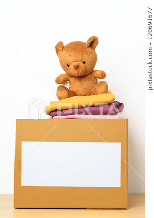 Kid Donation, Charity, Volunteer, Giving and Delivery Concept. Hand donate Bear doll and Clothes into cardboard box at home for support and help poor, refugee and homeless people. Copy space for text Kid Donation, Charity, Volunteer, Giving and Delivery Concept. Hand donate Bear doll and Clothes into cardboard box at home for support and help poor, refugee and homeless people. Copy space for text 120691677