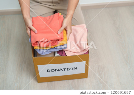 Donation, Charity, Volunteer, Giving and Delivery Concept. Hand holding Clothes into Donation box at home or office for support and help poor, refugee and homeless people. Copy space for text Donation, Charity, Volunteer, Giving and Delivery Concept. Hand holding Clothes into Donation box at home or office for support and help poor, refugee and homeless people. Copy space for text 120691697