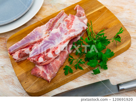 Fresh raw pork ribs on kitchen board with parsley, meat with bone. Cooking delicious food or grilling 120691920