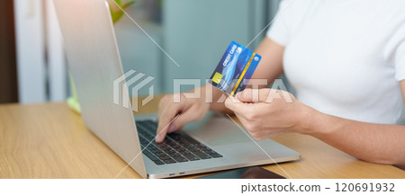 woman hand holding credit card and using laptop with mobile phone for online shopping while making order. Marketplace platform website, technology, ecommerce, digital banking and online payment 120691932