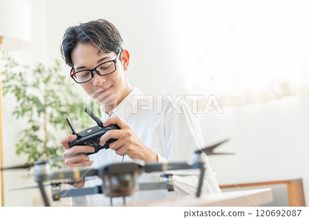 A young man operating a drone 120692087
