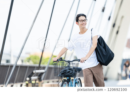 Young man pushing a bicycle Young man pushing a bicycle 120692100