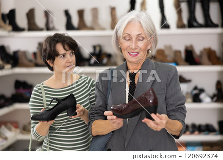 Two women are shopping in shoe store, choose woman dress shoes, classic shoes 120692374