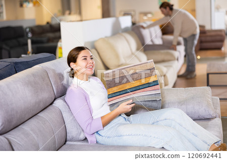 Young woman chooses upholstery fabric 120692441