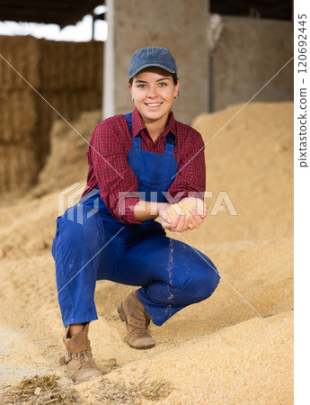 Smiling female farmer with handful of soybean husk feed in her hands 120692445