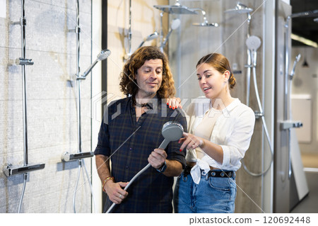 in plumbing department,man and woman examine shower head and quality of metal coating. 120692448