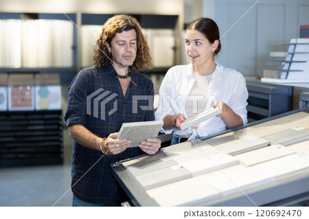 In construction mall,couple inspects drawing of decorative slabs for interior decoration 120692470