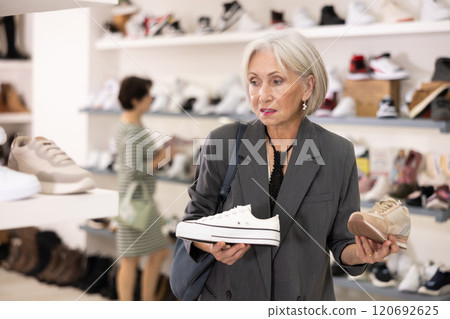 Senior woman takes samples from showcase and examines snickers Senior woman takes samples from showcase and examines snickers 120692625