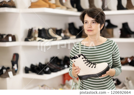 Woman takes samples from showcase and examines shoes Woman takes samples from showcase and examines shoes 120692664