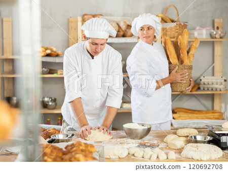 Man works in bakery as baker, kneads dough, works with flour. 120692708