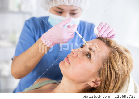 Qualified cosmetologist giving beauty injections for face skin rejuvenating and tightening for female client in aesthetic medicine office 120692725