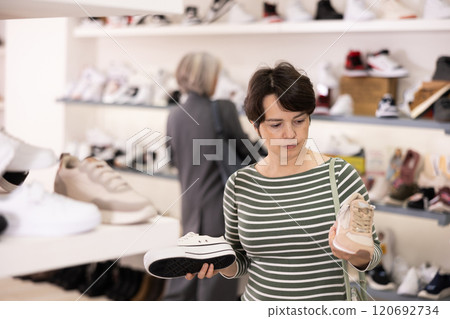 Woman takes samples from showcase and examines snickers 120692734