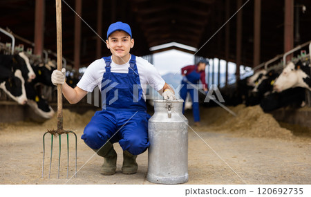 Farmer holding can and rake at cow farm 120692735