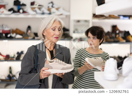 Two women are shopping in shoe store, choose snickers Two women are shopping in shoe store, choose snickers 120692761