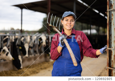 Farmer woman stands with rake at cow farm Farmer woman stands with rake at cow farm 120692805
