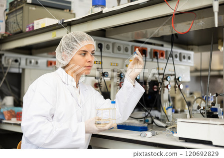 Concentrated young woman checking reagent reaction in test tube during scientific research in modern laboratory Concentrated young woman checking reagent reaction in test tube during scientific research in modern laboratory 120692829