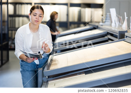 Focused woman choosing wall tiling materials in hardware shop 120692835