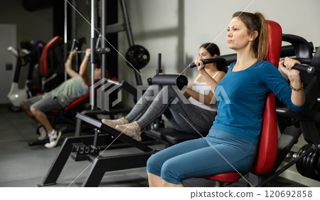 Caucasian woman doing exercises on shoulder press machine in gym Caucasian woman doing exercises on shoulder press machine in gym 120692858