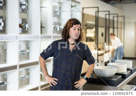 Confident male customer looking around in bathroom section of hardware store 120692875