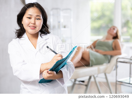Asian professional cosmetologist advertising facial procedure to patients Asian professional cosmetologist advertising facial procedure to patients 120693049