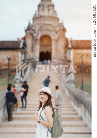 Young asian woman traveler in white dress with hat and bag traveling in Wat Phra That Lampang Luang, Tourist visit at Lampang, Thailand.. Asia Travel, Vacation and summer holiday concept 120693620