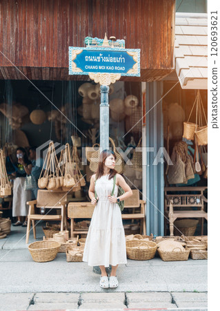 Young asian woman traveler in dress with hat traveling to wicker shop on Chang Moi Kao Road, Tourist visit at the old city in Chang Mai, Thailand. Asia Travel, Vacation and summer holiday concept Young asian woman traveler in dress with hat traveling to wicker shop on Chang Moi Kao Road, Tourist visit at the old city in Chang Mai, Thailand. Asia Travel, Vacation and summer holiday concept 120693621