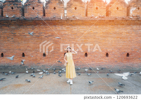 Young asian woman traveler in Yellow dress with hat and bag traveling on Tha Pae Gate, Tourist visit at the old city in Chang Mai, Thailand. Asia Travel, Vacation and summer holiday concept 120693622