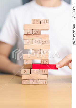hand pulling wooden block tower on table. Business planning, Risk Management, Solution, leader, strategy, Crisis, falling Business, and Economic recession concept hand pulling wooden block tower on table. Business planning, Risk Management, Solution, leader, strategy, Crisis, falling Business, and Economic recession concept 120693736
