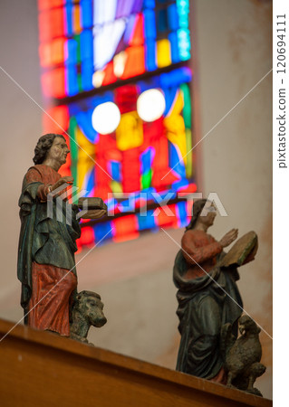 Religious Statues Beautifully Crafted with a Stunning and Colorful Stained Glass Background Religious Statues Beautifully Crafted with a Stunning and Colorful Stained Glass Background 120694111