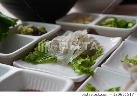 Sliced squid on lettuce leaf in white plate on wooden table 120695517