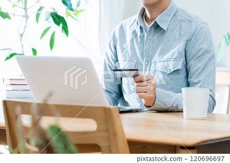 A man's hand looking at a credit card 120696697