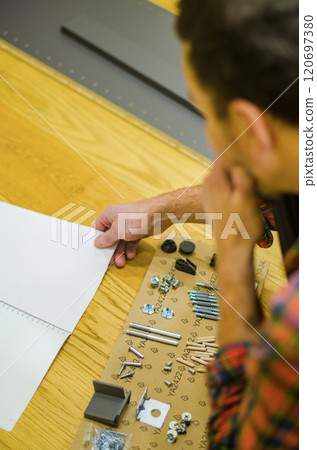 man thinking about furniture assembly instructions and some furniture details . High quality photo man thinking about furniture assembly instructions and some furniture details . High quality photo 120697380
