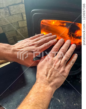 male warms his hands near the stove with burning coals. High quality photo male warms his hands near the stove with burning coals. High quality photo 120697386