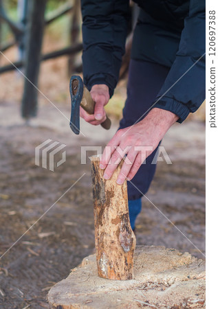 Chopping wood for the fire with an axe. A man's hand with an axe chopping wood. High quality photo 120697388