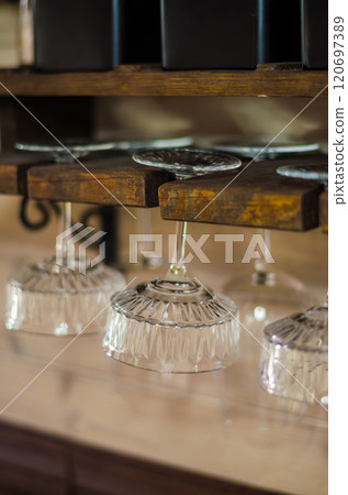 Elegant crystal glasses hanging on a rustic wooden rack in a cozy kitchen. High quality photo Elegant crystal glasses hanging on a rustic wooden rack in a cozy kitchen. High quality photo 120697389
