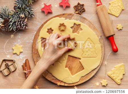 Woman making christmas cookies using star shaped cutters on wooden board Woman making christmas cookies using star shaped cutters on wooden board 120697556