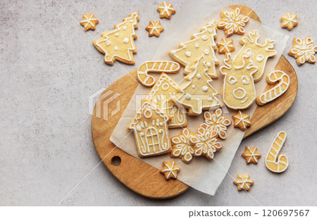 Christmas cookies decorated with icing lying on wooden board 120697567