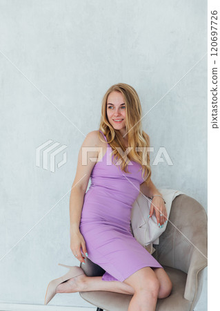 Beautiful woman smiling in purple dress sitting on chair 120697726
