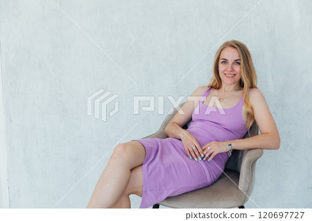 Beautiful woman smiling in purple dress sitting on chair 120697727