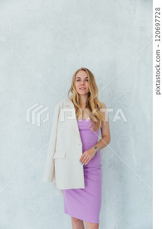 blonde woman smiling in purple dress and white jacket 120697728