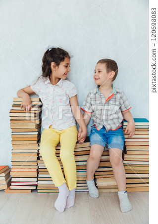 Boy And Girl Sitting On Stacks Of Educational Books Boy And Girl Sitting On Stacks Of Educational Books 120698083