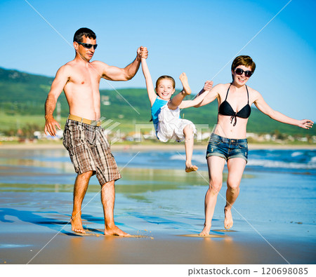 Beautiful family with daughter playing on the beach 120698085