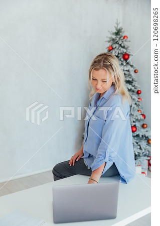 Business blonde woman with laptop online at the christmas tree Business blonde woman with laptop online at the christmas tree 120698265