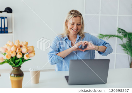 woman with laptop online smiling and showing hands heart 120698267