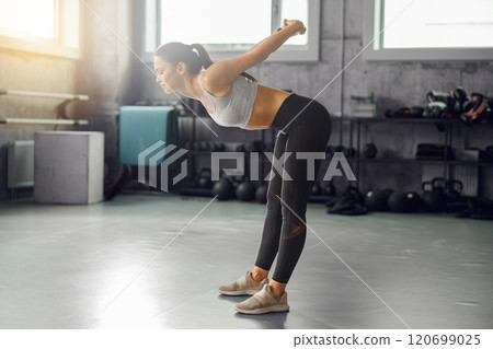 A Focused Woman is Powerfully Exercising in a Contemporary and Modern Gym Setting A Focused Woman is Powerfully Exercising in a Contemporary and Modern Gym Setting 120699025