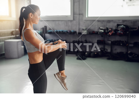 A woman stretching at the gym to enhance flexibility and overall fitness outcomes 120699040