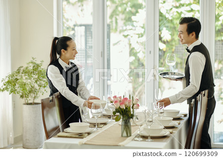 Setting Up Table in Elegant Restaurant with Waitstaff Coordinating 120699309