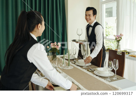 Smiling Waitstaff Setting Up Elegant Dinner Service Smiling Waitstaff Setting Up Elegant Dinner Service 120699317