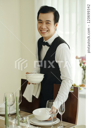 Smiling Waiter Setting Up Table in Restaurant 120699342